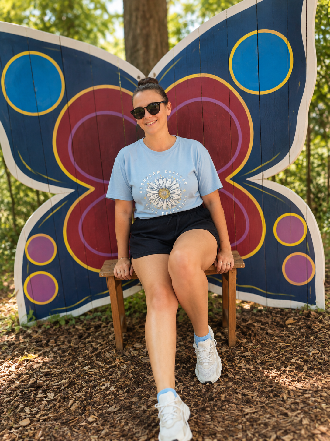 Teri Astyn, therapist at Feeling Being Therapy, seated in front of a colourful butterfly art installation