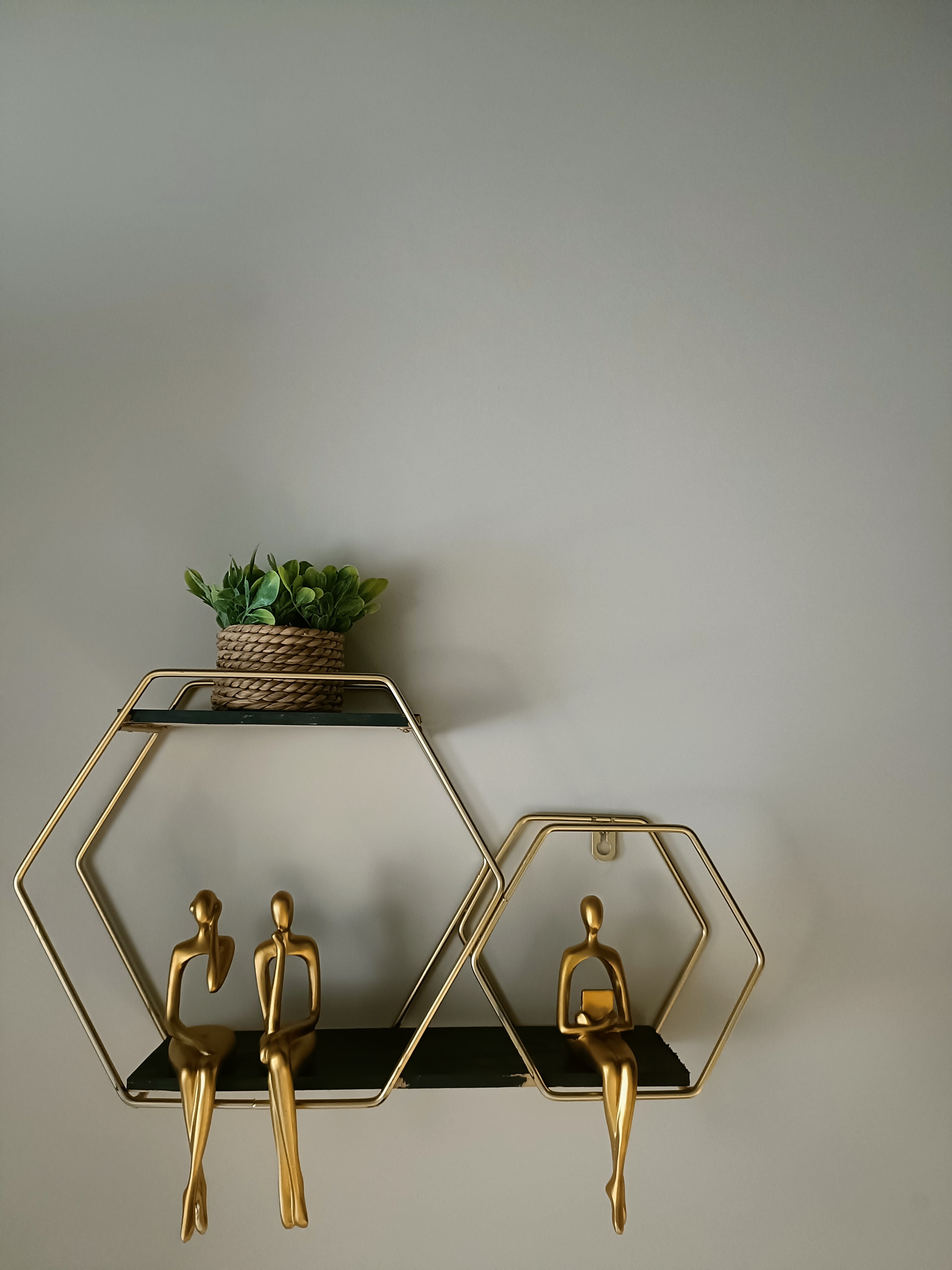Gold geometric shelves with contemplative figures — a reminder that transitions invite us to pause and reflect